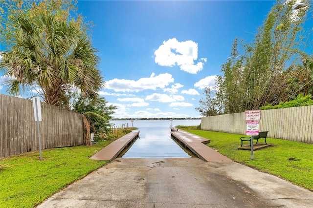 dock area featuring a yard, a water view, and fence