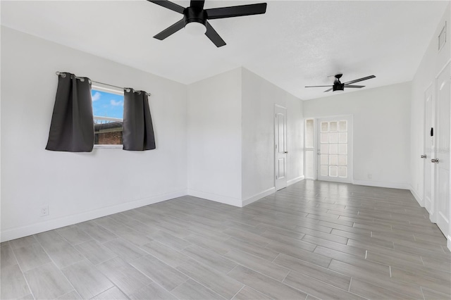 spare room featuring ceiling fan, baseboards, and wood finished floors