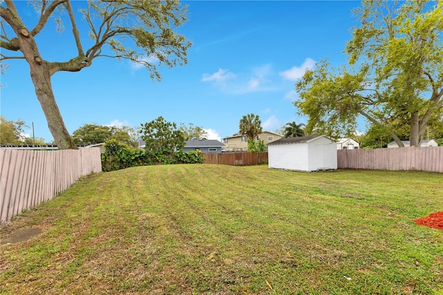 view of yard featuring an outbuilding, a fenced backyard, and a shed