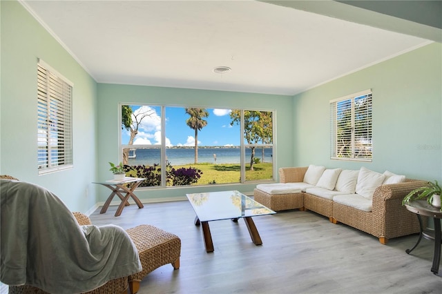 living area featuring a water view, crown molding, baseboards, and wood finished floors