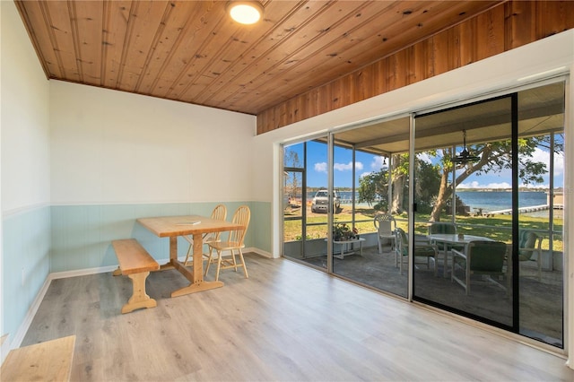 dining area with a water view, wood ceiling, wood finished floors, and wainscoting