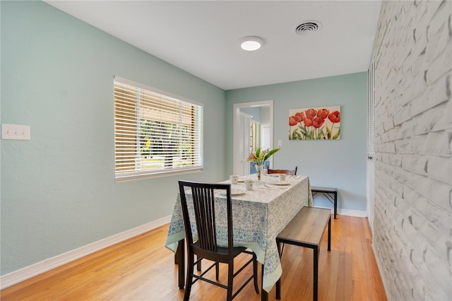 dining space with baseboards, visible vents, and light wood finished floors