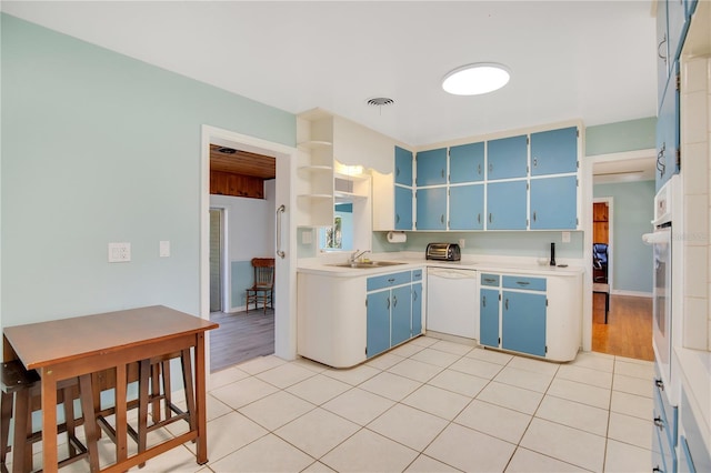 kitchen with a sink, visible vents, blue cabinetry, dishwasher, and open shelves