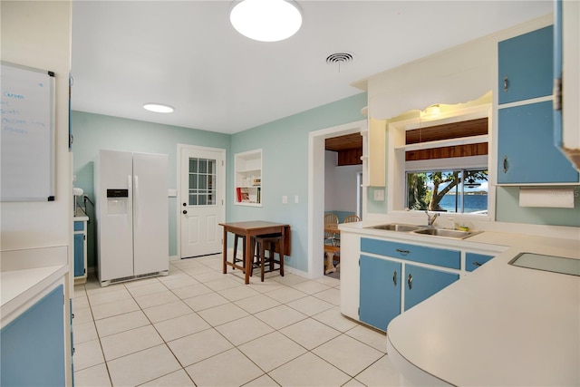 kitchen featuring light tile patterned floors, visible vents, blue cabinets, light countertops, and white fridge with ice dispenser