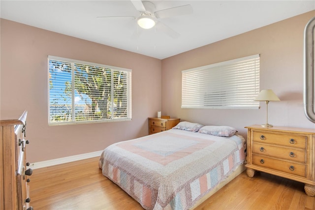 bedroom with a ceiling fan, light wood-style flooring, and baseboards