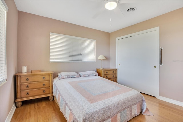 bedroom with light wood-style floors, baseboards, visible vents, and ceiling fan