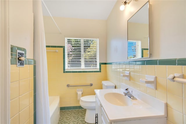 bathroom with tile patterned flooring, toilet, a wainscoted wall, vanity, and tile walls