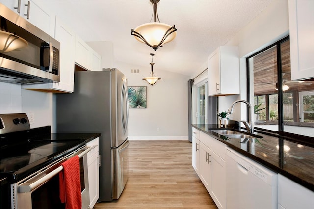 kitchen featuring lofted ceiling, white cabinetry, appliances with stainless steel finishes, and a sink