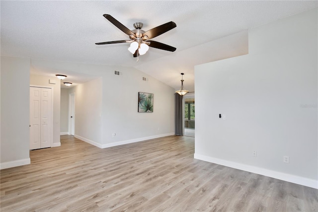 spare room featuring light wood-type flooring, ceiling fan, lofted ceiling, and baseboards