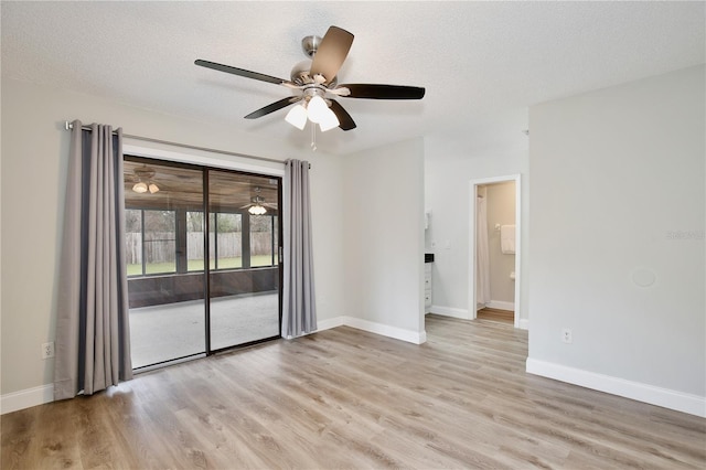 unfurnished room with a textured ceiling, light wood-style flooring, and baseboards