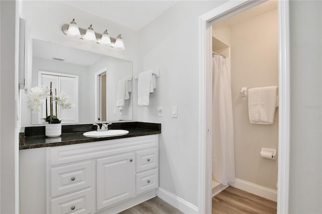 full bathroom with vanity, baseboards, and wood finished floors