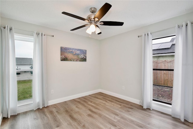 spare room with a wealth of natural light, light wood-style flooring, and baseboards