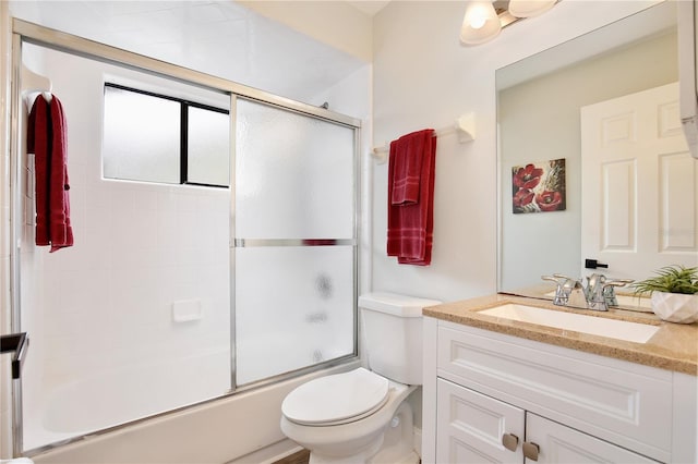 bathroom featuring toilet, combined bath / shower with glass door, and vanity