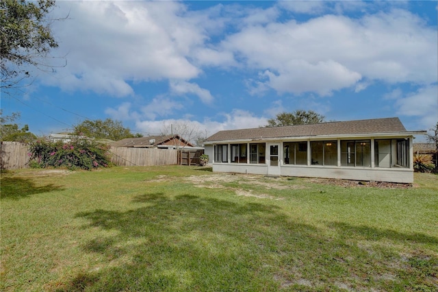 rear view of property featuring a lawn, a fenced backyard, and a sunroom