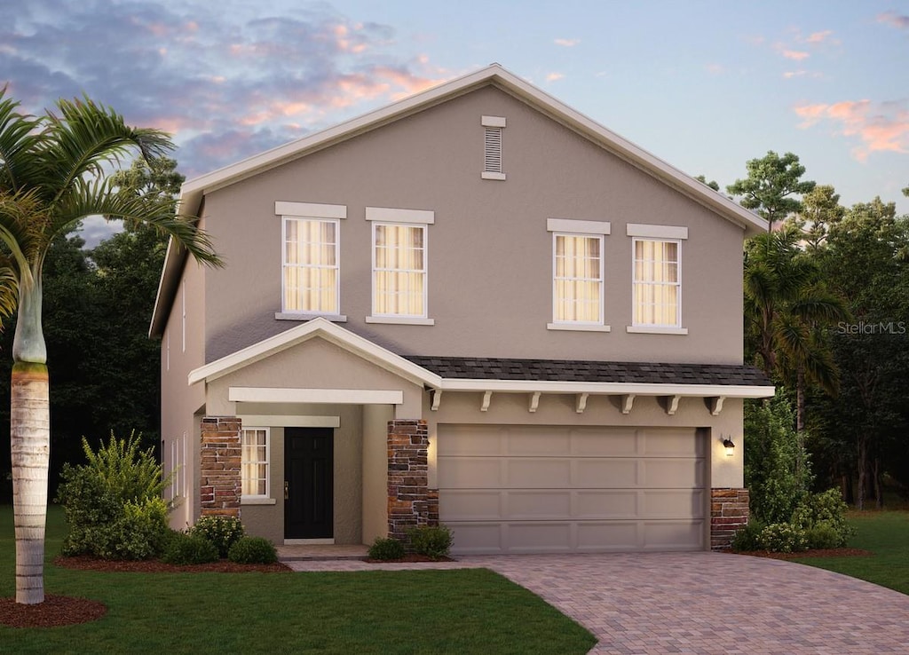 view of front of home with stone siding, decorative driveway, a garage, and stucco siding