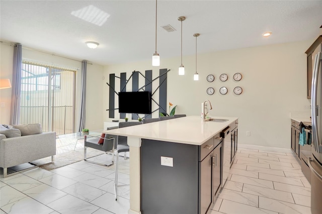 kitchen with a sink, open floor plan, marble finish floor, hanging light fixtures, and light countertops