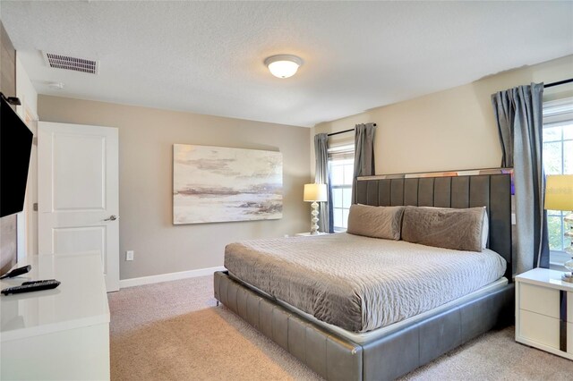 bedroom featuring baseboards, multiple windows, visible vents, and light colored carpet