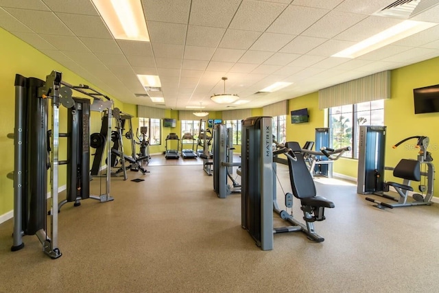 exercise room featuring a paneled ceiling, baseboards, and visible vents