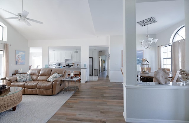 living area featuring high vaulted ceiling, wood finished floors, and ceiling fan with notable chandelier