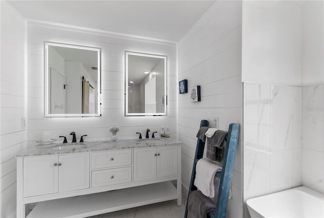 full bathroom with a freestanding tub, a sink, tile walls, and double vanity