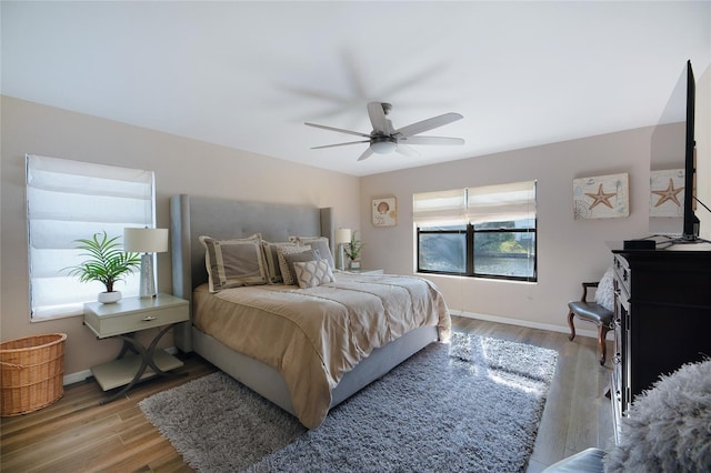 bedroom with wood finished floors, a ceiling fan, and baseboards