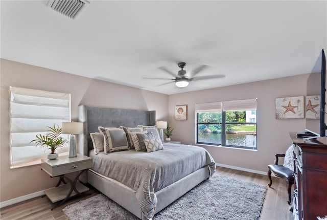 bedroom featuring light wood-type flooring, visible vents, ceiling fan, and baseboards