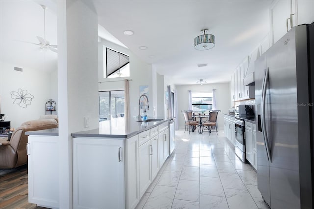 kitchen featuring marble finish floor, dark countertops, appliances with stainless steel finishes, open floor plan, and white cabinetry