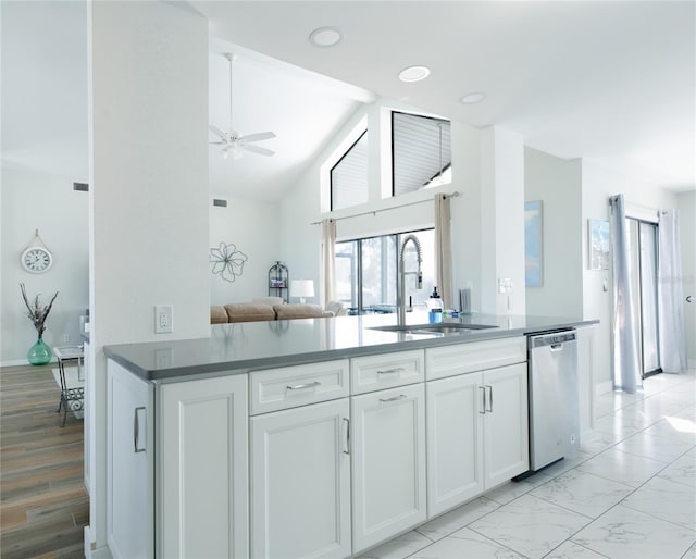 kitchen with white cabinets, dishwasher, dark countertops, open floor plan, and a sink