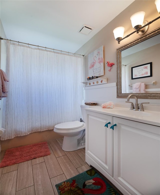 bathroom featuring toilet, vanity, visible vents, and wood finish floors