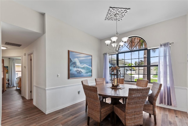 dining space with dark wood-type flooring, visible vents, baseboards, and an inviting chandelier