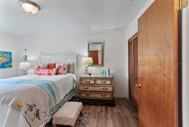 bedroom with a closet, visible vents, and dark wood-style flooring