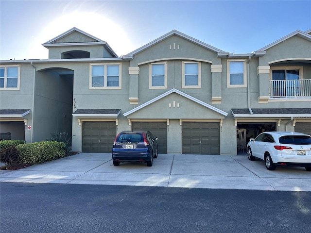 townhome / multi-family property featuring driveway, a garage, and stucco siding