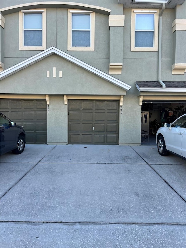 townhome / multi-family property with concrete driveway, an attached garage, and stucco siding