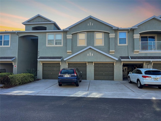 townhome / multi-family property featuring a garage, driveway, and stucco siding