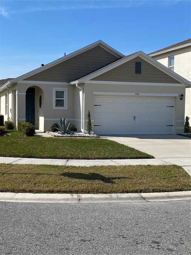 view of front of home with a garage, driveway, and stucco siding