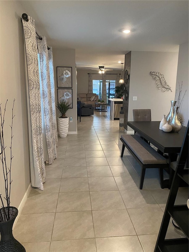 hall featuring light tile patterned flooring and baseboards