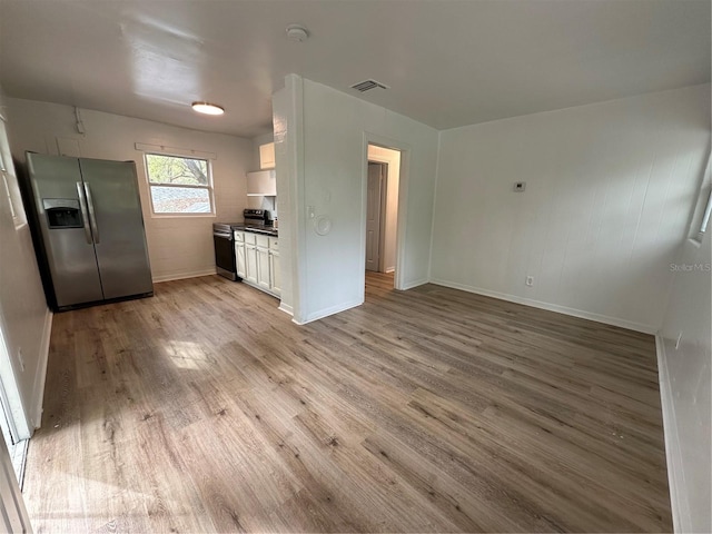 kitchen with visible vents, white cabinetry, appliances with stainless steel finishes, light wood finished floors, and dark countertops