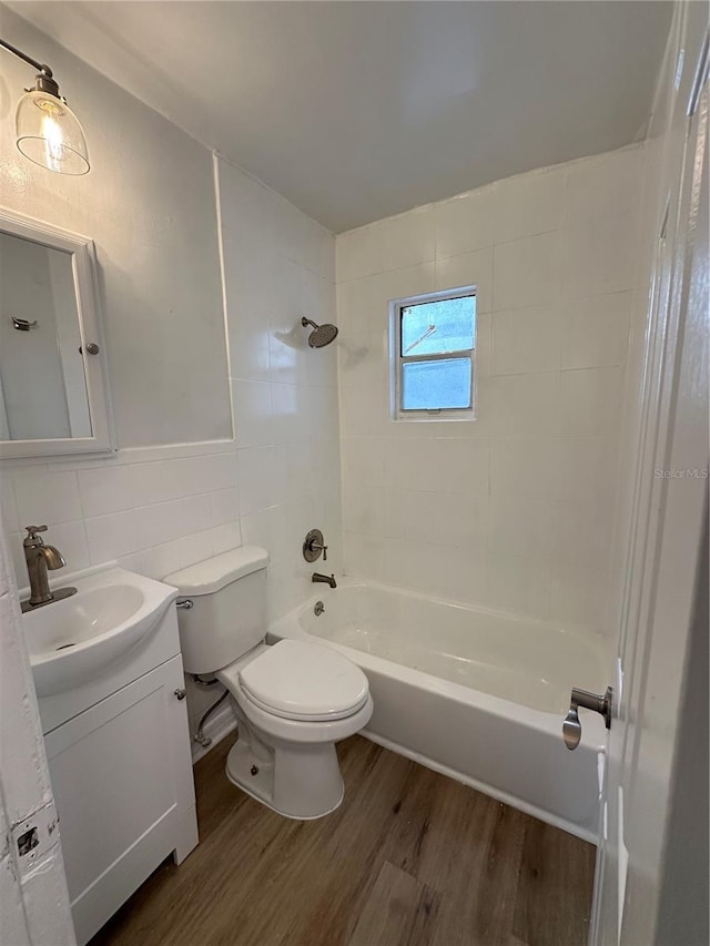 full bathroom featuring toilet, shower / bath combination, wood finished floors, vanity, and tile walls