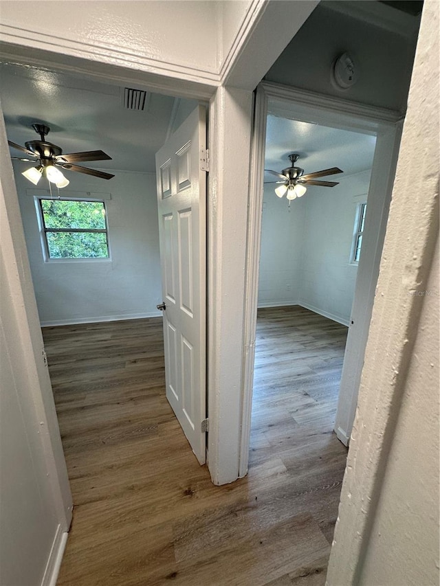 corridor with baseboards, visible vents, and wood finished floors