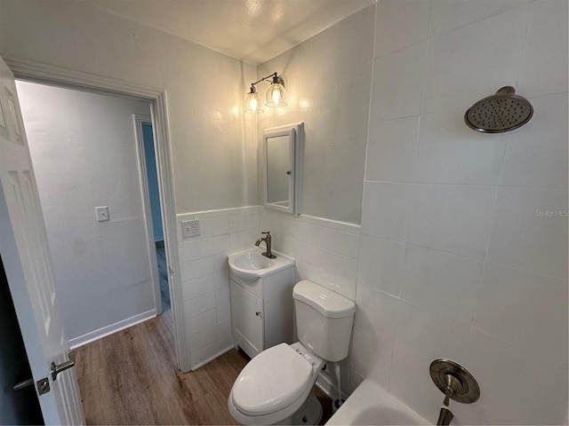 bathroom featuring tile walls, toilet, wainscoting, vanity, and wood finished floors