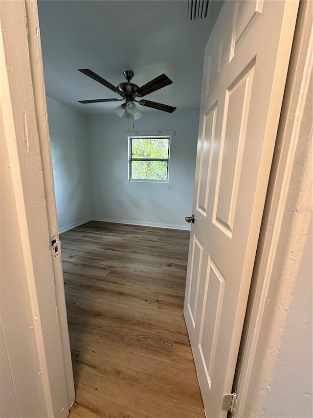 unfurnished bedroom with dark wood-style floors, visible vents, baseboards, and a ceiling fan