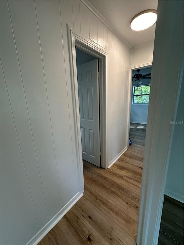 hallway with baseboards, ornamental molding, and wood finished floors