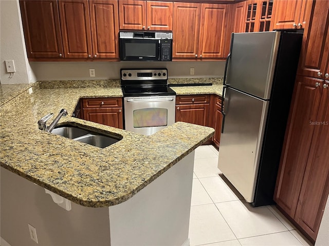 kitchen featuring a peninsula, appliances with stainless steel finishes, a sink, and light stone countertops