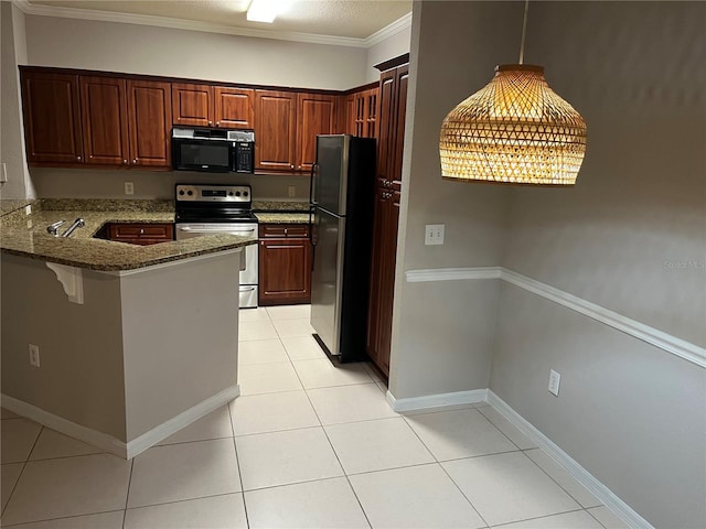 kitchen with hanging light fixtures, appliances with stainless steel finishes, light tile patterned flooring, dark stone countertops, and a peninsula