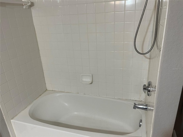 bathroom featuring  shower combination and a textured wall