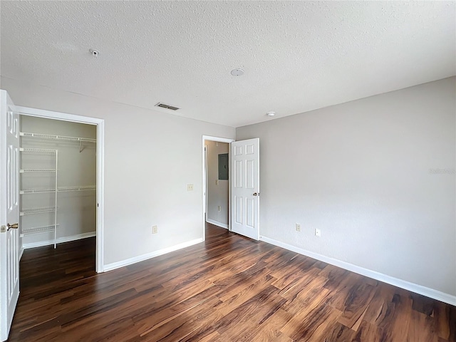 unfurnished bedroom featuring electric panel, baseboards, dark wood-style flooring, a textured ceiling, and a closet