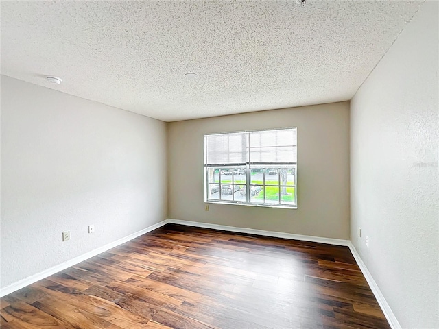 unfurnished room with baseboards, dark wood finished floors, and a textured ceiling