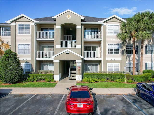 view of property featuring uncovered parking and stairs