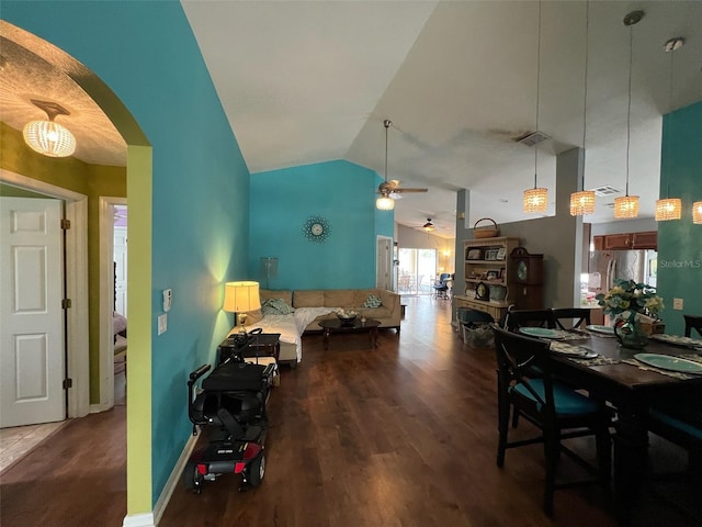 dining area featuring arched walkways, wood finished floors, a ceiling fan, baseboards, and vaulted ceiling