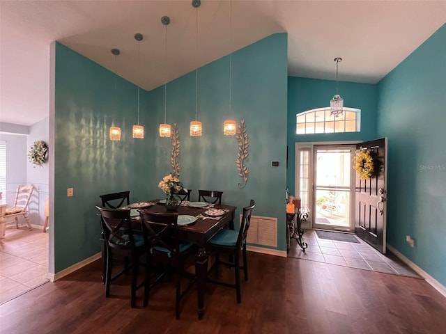 dining space with high vaulted ceiling, visible vents, baseboards, and wood finished floors